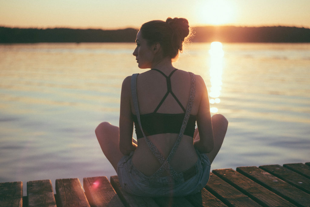 Girl sitting on a dock with sunset