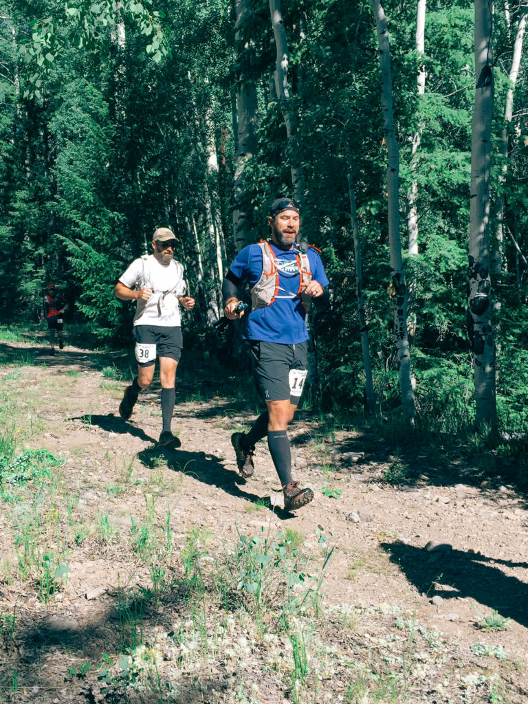Two men running on a trail outdoors